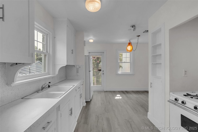 kitchen featuring white cabinetry, white appliances, sink, and hanging light fixtures