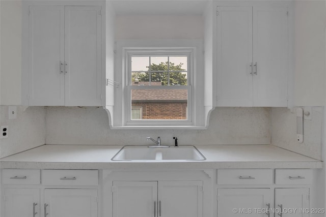 kitchen featuring tasteful backsplash, white cabinetry, and sink