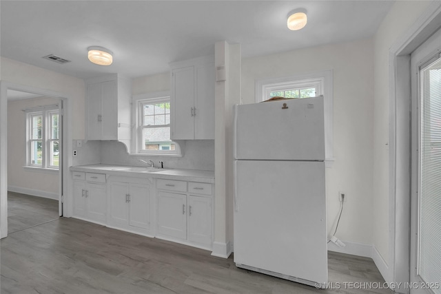 kitchen featuring sink, light hardwood / wood-style flooring, white cabinets, and white fridge