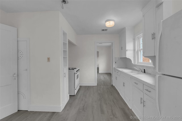 kitchen with sink, white cabinets, white appliances, and light hardwood / wood-style flooring