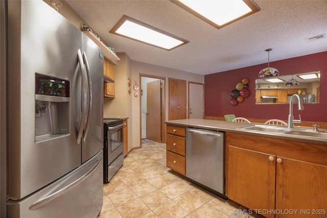 kitchen with pendant lighting, sink, a textured ceiling, and appliances with stainless steel finishes