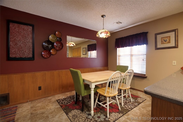 tiled dining area with wooden walls and a textured ceiling