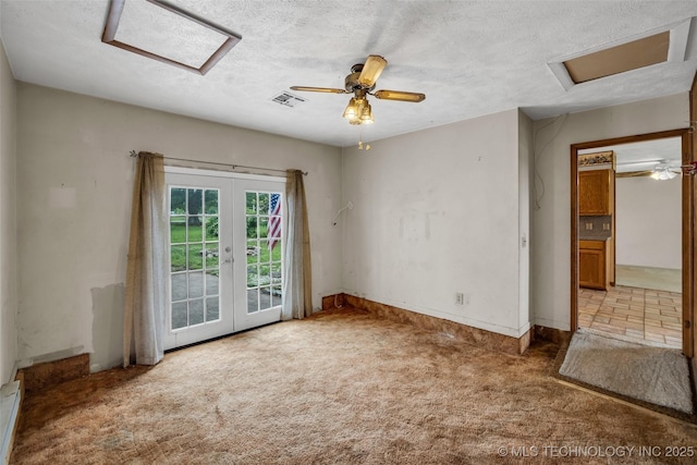 carpeted spare room with ceiling fan, french doors, and a textured ceiling