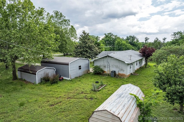 back of house with a yard, an outdoor structure, and central AC unit