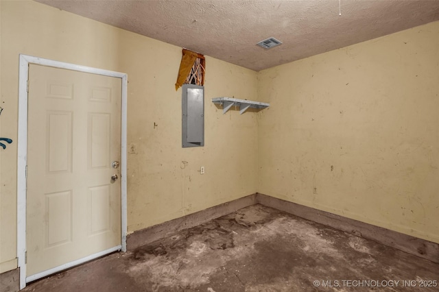 empty room featuring electric panel, concrete floors, and a textured ceiling