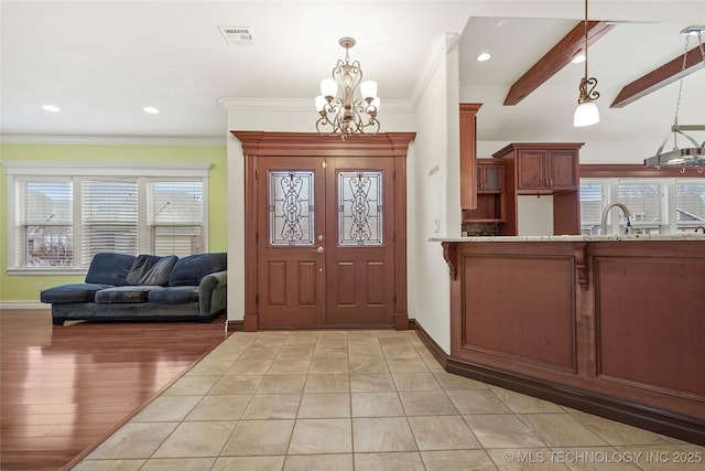 foyer entrance with beamed ceiling, sink, a chandelier, ornamental molding, and light hardwood / wood-style floors