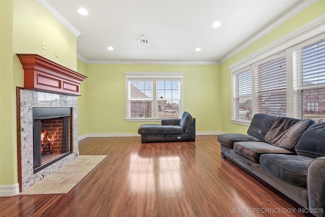 living room with ornamental molding, a high end fireplace, hardwood / wood-style floors, and a wealth of natural light