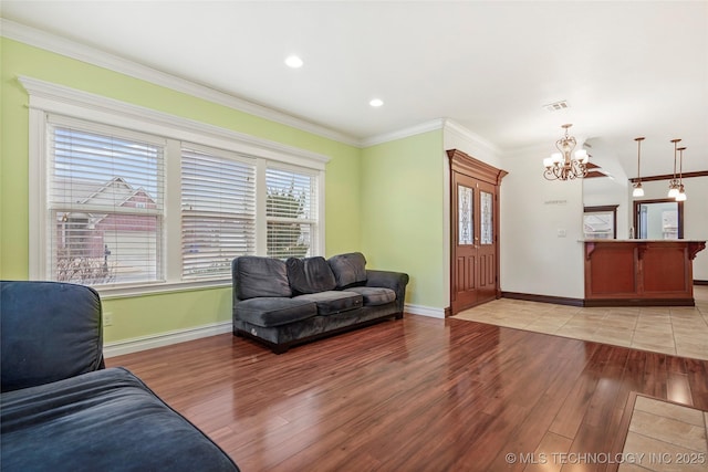 living room featuring crown molding, light hardwood / wood-style floors, and a chandelier