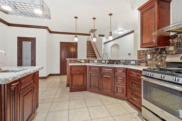 kitchen featuring hanging light fixtures, stainless steel range with gas cooktop, sink, and wall chimney exhaust hood