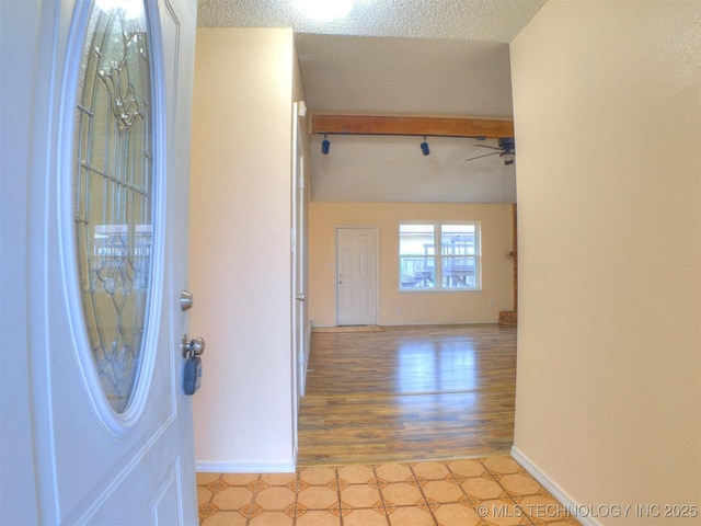 entryway with beamed ceiling, ceiling fan, and a textured ceiling