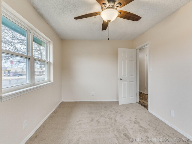 carpeted spare room featuring ceiling fan and a textured ceiling