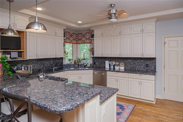 kitchen featuring a kitchen breakfast bar, light hardwood / wood-style floors, white cabinets, decorative light fixtures, and kitchen peninsula