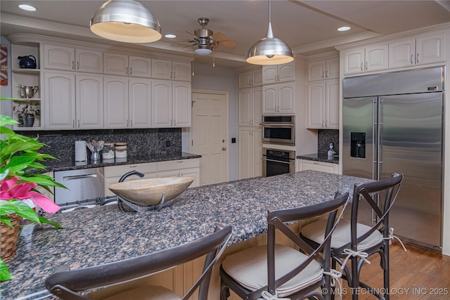 kitchen with pendant lighting, wood-type flooring, white cabinets, decorative backsplash, and stainless steel appliances