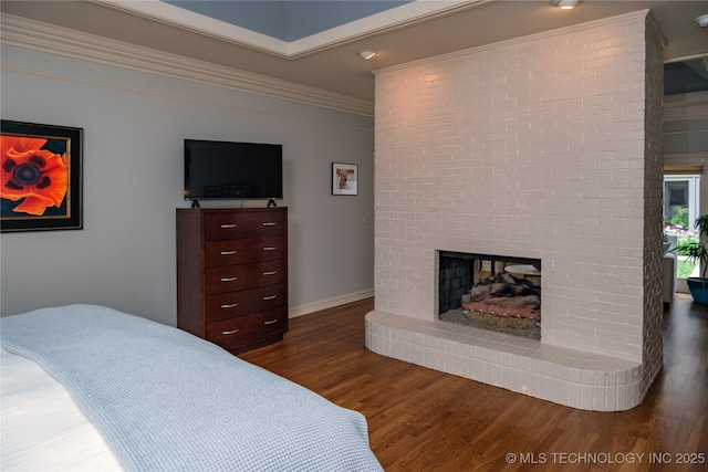 bedroom featuring ornamental molding, a brick fireplace, and dark hardwood / wood-style floors