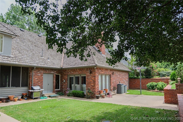 rear view of house featuring a lawn, a patio, and central air condition unit