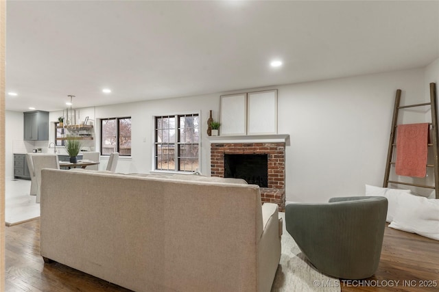 living room featuring a brick fireplace, sink, and dark hardwood / wood-style floors