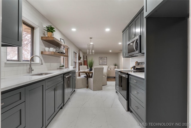 kitchen with pendant lighting, sink, gray cabinets, and stainless steel appliances