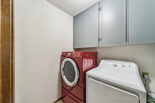 clothes washing area featuring cabinets and independent washer and dryer