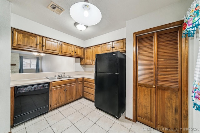 kitchen with sink, light tile patterned floors, a textured ceiling, and black appliances