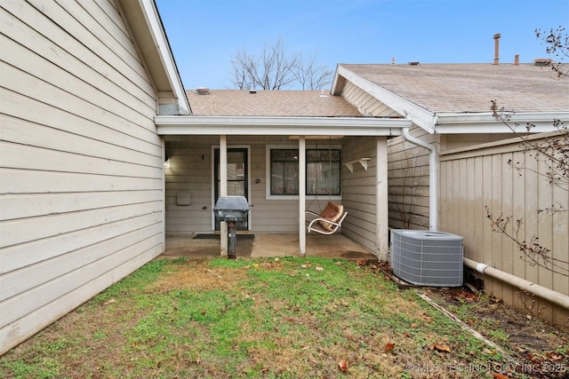 view of exterior entry with a lawn, a patio area, and central air condition unit