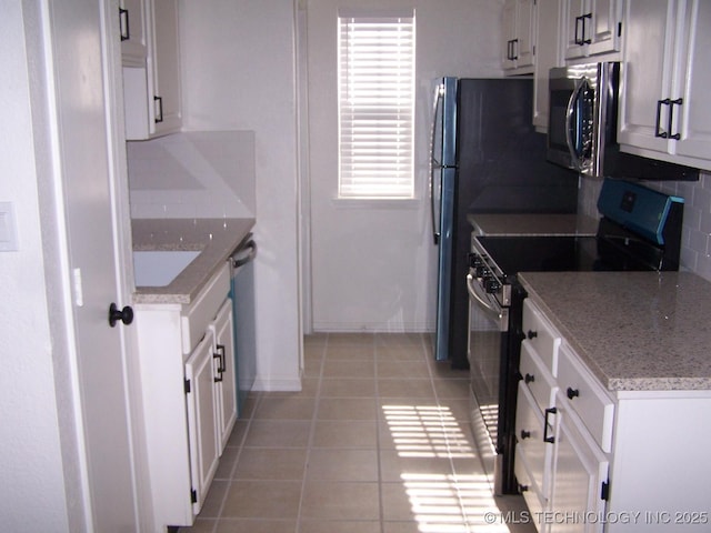 kitchen featuring appliances with stainless steel finishes, tasteful backsplash, white cabinets, light tile patterned floors, and light stone countertops