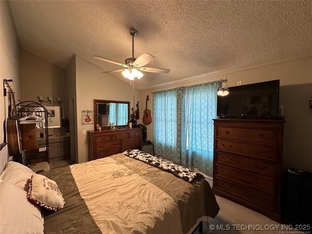 bedroom featuring ceiling fan, vaulted ceiling, and a textured ceiling