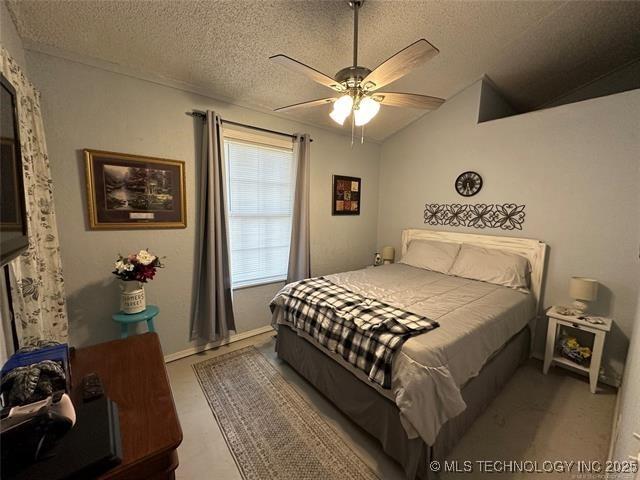 bedroom featuring ceiling fan, lofted ceiling, and a textured ceiling