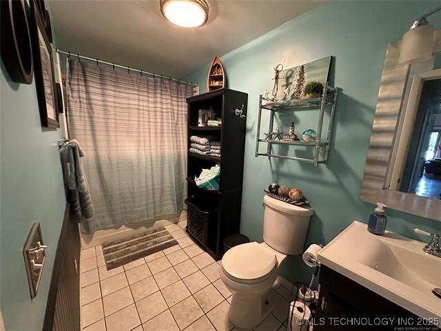 bathroom with a shower with curtain, vanity, tile patterned floors, and toilet