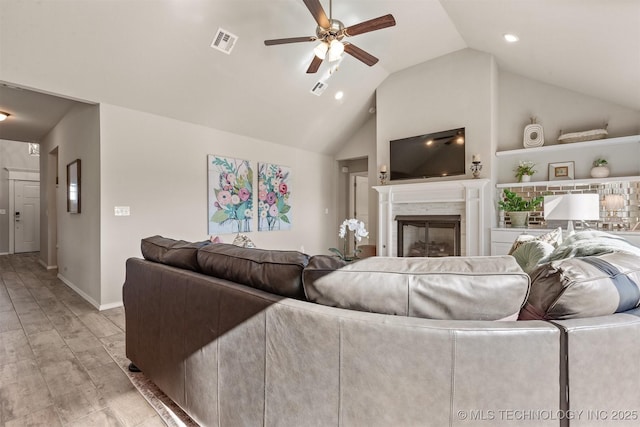 living room with ceiling fan, vaulted ceiling, and light wood-type flooring