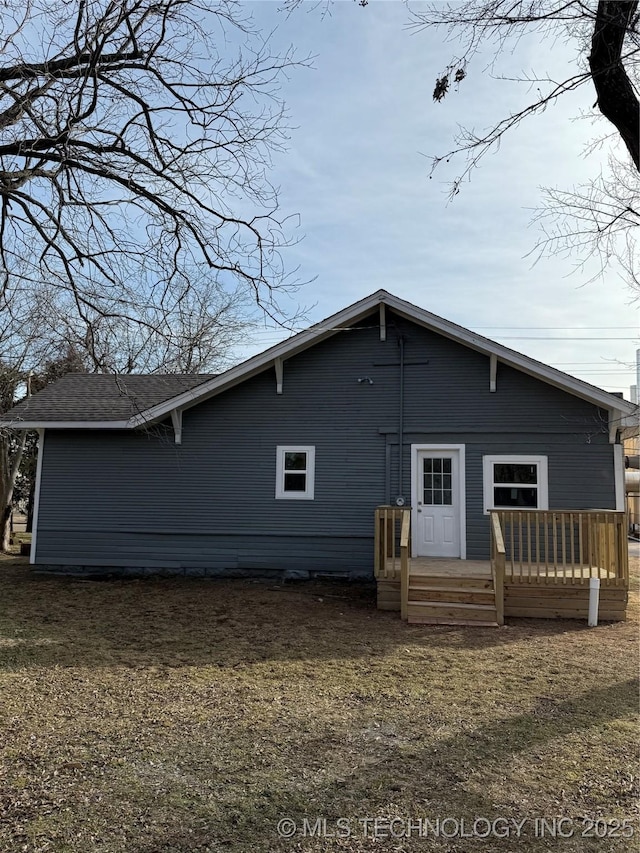 back of property with a wooden deck and a lawn