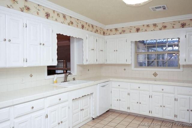 kitchen with light tile patterned flooring, sink, white cabinetry, tile counters, and white dishwasher