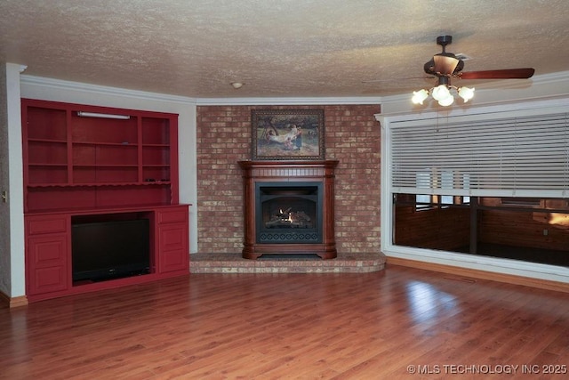 unfurnished living room featuring crown molding, a brick fireplace, wood-type flooring, and a textured ceiling