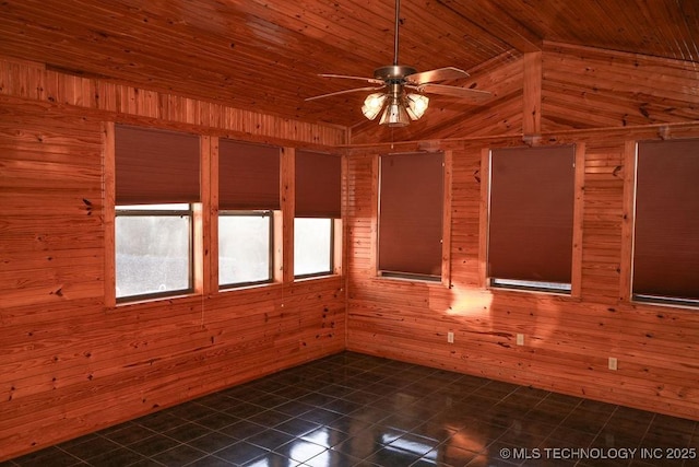 spare room featuring ceiling fan, wooden walls, dark tile patterned flooring, and wooden ceiling