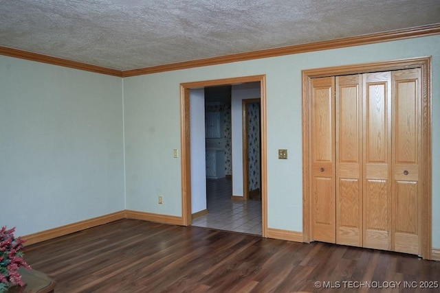 unfurnished bedroom with dark wood-type flooring, ornamental molding, a closet, and a textured ceiling