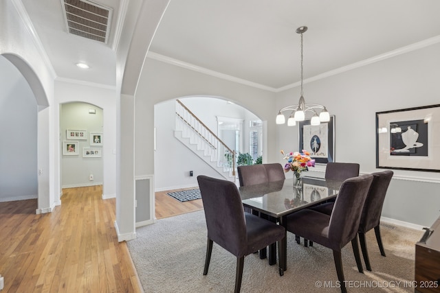 dining space with crown molding, a chandelier, and light hardwood / wood-style flooring