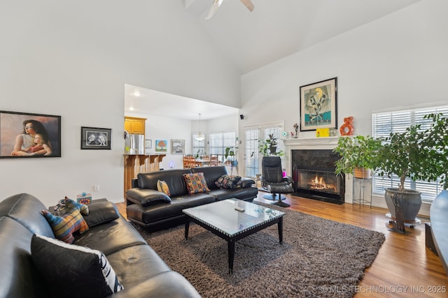 living room featuring ceiling fan, high vaulted ceiling, and light wood-type flooring