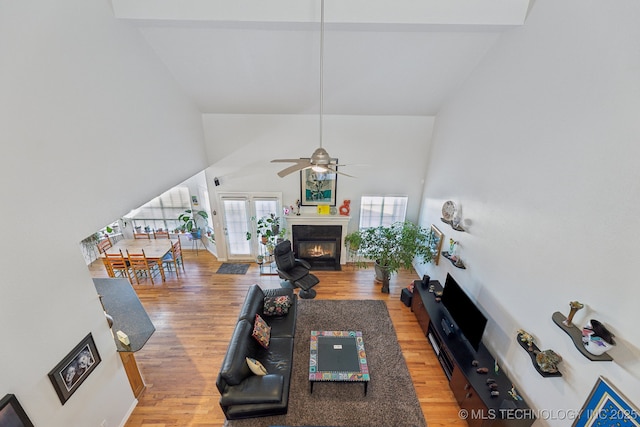 living room with wood-type flooring, a towering ceiling, and ceiling fan