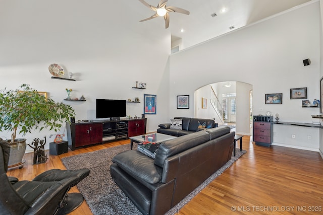 living room with hardwood / wood-style flooring, ceiling fan, and a high ceiling