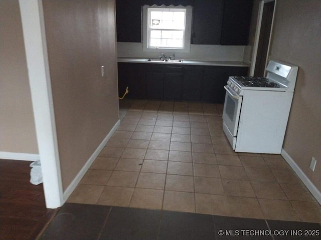 kitchen featuring sink, white gas stove, and light tile patterned floors