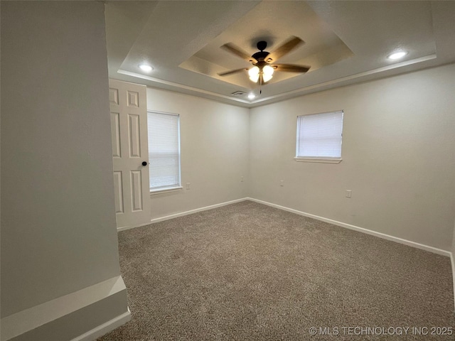 spare room featuring a raised ceiling, carpet flooring, and ceiling fan