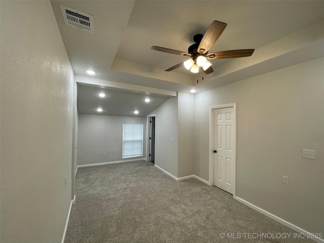 carpeted empty room with ceiling fan and a tray ceiling