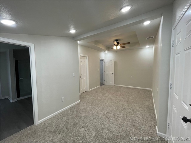 empty room with a tray ceiling, carpet floors, a textured ceiling, and ceiling fan