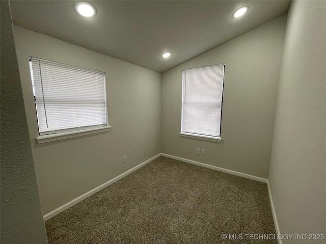 unfurnished room with lofted ceiling and dark carpet