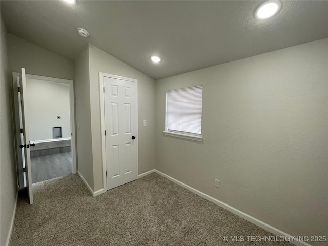 unfurnished bedroom featuring lofted ceiling and carpet