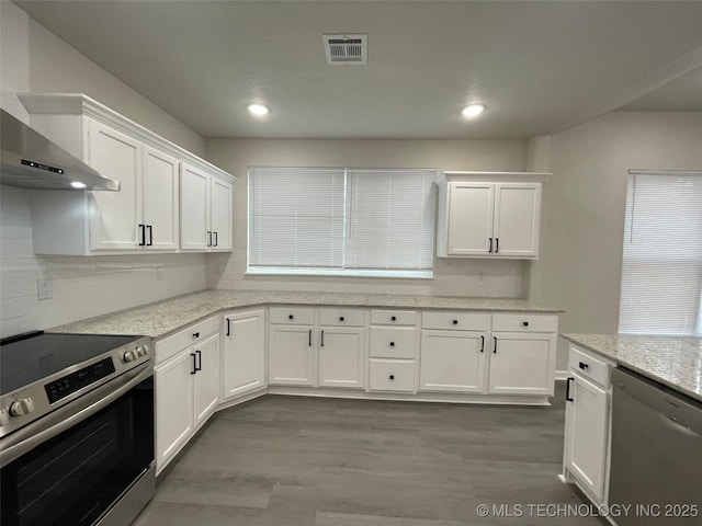 kitchen with wall chimney range hood, stainless steel appliances, and white cabinets