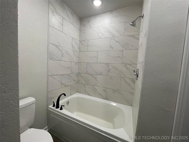 bathroom featuring tiled shower / bath and toilet