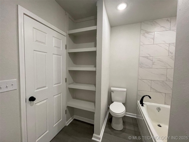 bathroom with built in shelves, toilet, and a bathing tub