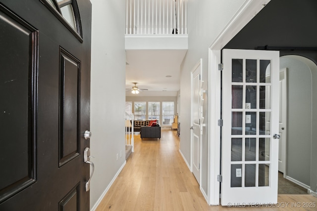 foyer featuring light hardwood / wood-style floors, ceiling fan, and a high ceiling