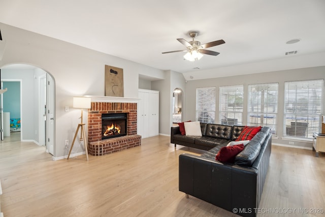 living room with ceiling fan, a fireplace, and light hardwood / wood-style flooring