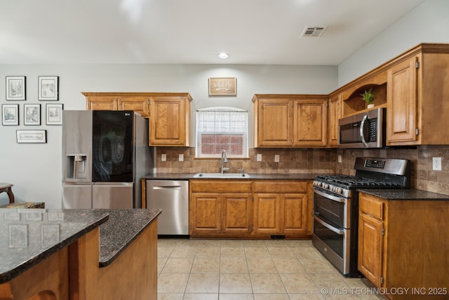 kitchen featuring sink, appliances with stainless steel finishes, dark stone countertops, backsplash, and light tile patterned flooring